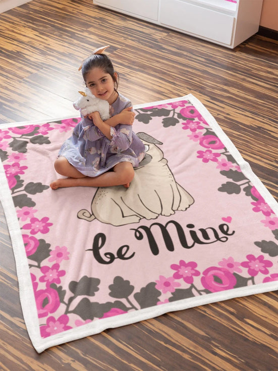 Image of a girl sitting on a be mine Pug blanket