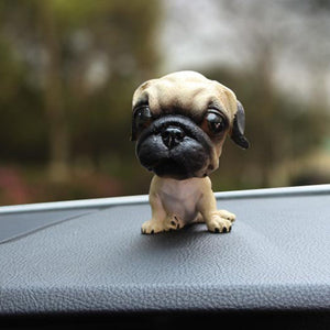 Image of a sitting Pug bobblehead on a car dashboard