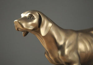 Close up image of a golden weimaraner statue made of brass and resin