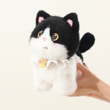 Load image into Gallery viewer, A black and white plush cat toy with large yellow eyes and a white ruffled collar, being held by a person's hand against a plain light background.
