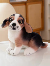 Load image into Gallery viewer, A realistic plush puppy toy with large expressive eyes, floppy ears, and a black, white, and tan beagle-like coat, sitting on a white surface in a softly blurred indoor setting.