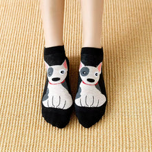 Load image into Gallery viewer, A person wearing black ankle socks with a cartoon dog face on the front, standing on a woven beige mat.