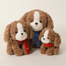 Load image into Gallery viewer, Three brown and white cocker spaniel plush puppy toys of different sizes, styled together on a light beige background. The two smaller plushies wear red knit scarves, and the larger one in the back wears a blue knit vest.