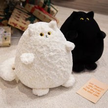 Load image into Gallery viewer, Two round plush cat toys on a carpeted floor, one white fluffy cat in front and one black plush cat behind it, with wrapped gifts and a small note card in the background.
