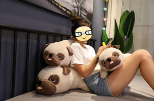 Image of a girl on the bed next to three Pug stuffed animals soft plush toys in different sizes