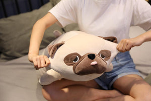 Image of a girl on the bed holding a Pug stuffed animal by his ears