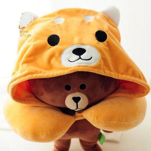 Image of a brown teddy bear wearing an orange shiba inu travel pillow and hoodie