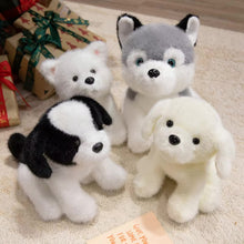 Load image into Gallery viewer, Four plush toy dogs in various poses on a textured surface with gift boxes in the background.