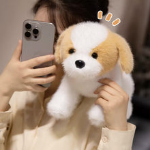 Load image into Gallery viewer, A person holding a plush puppy toy in front of their face while taking a mirror selfie with a smartphone. The puppy is white and tan with black eyes and a black nose, and there is a small decorative graphic above its head.