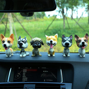 Image of six dog bobbleheads on a car dashboard including Corgi, Sitting Husky, Pug, Shiba Inu, Standing Husky, and Corgi