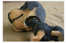 Load image into Gallery viewer, A close-up of a small black and tan rottweiler dog-shaped bobblehead lying on a textured beige fabric background.