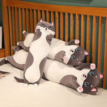 Load image into Gallery viewer, Three plush husky-shaped pillows arranged together on a bed in front of a wooden slatted headboard. The pillows are white and gray with pink paw pads and blue cartoon eyes.
