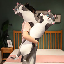 Load image into Gallery viewer, A person in a bedroom holding a large, plush, husky-shaped body pillow that stretches from the floor up to the ceiling. The pillow features a cartoonish gray and white cat design with blue eyes and pink accents.