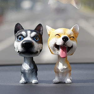 Image of two bobbleheads on a car dashboard shaped like a Husky and a smiling Shiba Inu