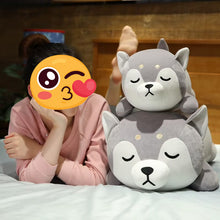 Load image into Gallery viewer, A person lying on a bed with their face covered by a winking emoji sticker, next to two plush husky toys stacked on top of each other. The background shows a wooden headboard and a cozy bedroom setting.