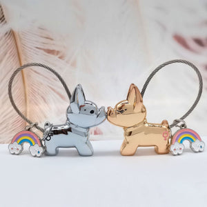 Image of two metallic frenchie keychains in the color boy silver and girl light gold kissing each other