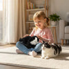 Child playing with a black and white cat on a carpeted floor in a bright room.