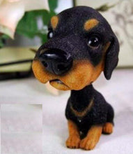 Load image into Gallery viewer, A small black and tan rottweiler dog figurine or plush toy sitting on a light surface, photographed indoors with a blurred background.