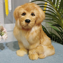 Load image into Gallery viewer, A small fluffy golden labradoodle  dog toy or plush pup sitting on a light blue surface, styled with pink flowers and a green plant in the background.