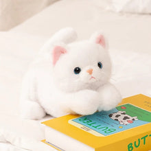 Load image into Gallery viewer, A white plush cat toy with pink inner ears and black eyes is posed on a white bed next to a yellow children's book titled "BUTTER.".