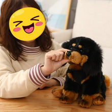 Load image into Gallery viewer, A person in a cream sweatshirt pets a black and tan Tibetan mastiff plush puppy toy on a wooden table. The person's face is covered by a yellow winking emoji sticker.