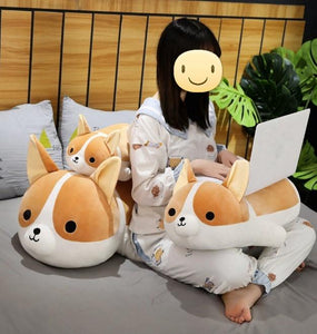 Image of a girl on the bed next to three Corgi stuffed animals soft plush toys in different sizes