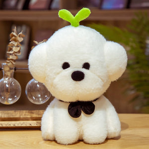 This image shows a cute Bichon Frise Stuffed Animal Plush Toy with a grass on it's head and sitting on the table.