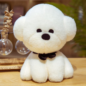This image shows a cute Bichon Frise Stuffed Animal Plush Toy with a black bow-tie in it's neck and sitting on the table.