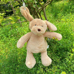 this image shows the cutest plush golden retriever soft toy hanging on a tree branch by its ear.