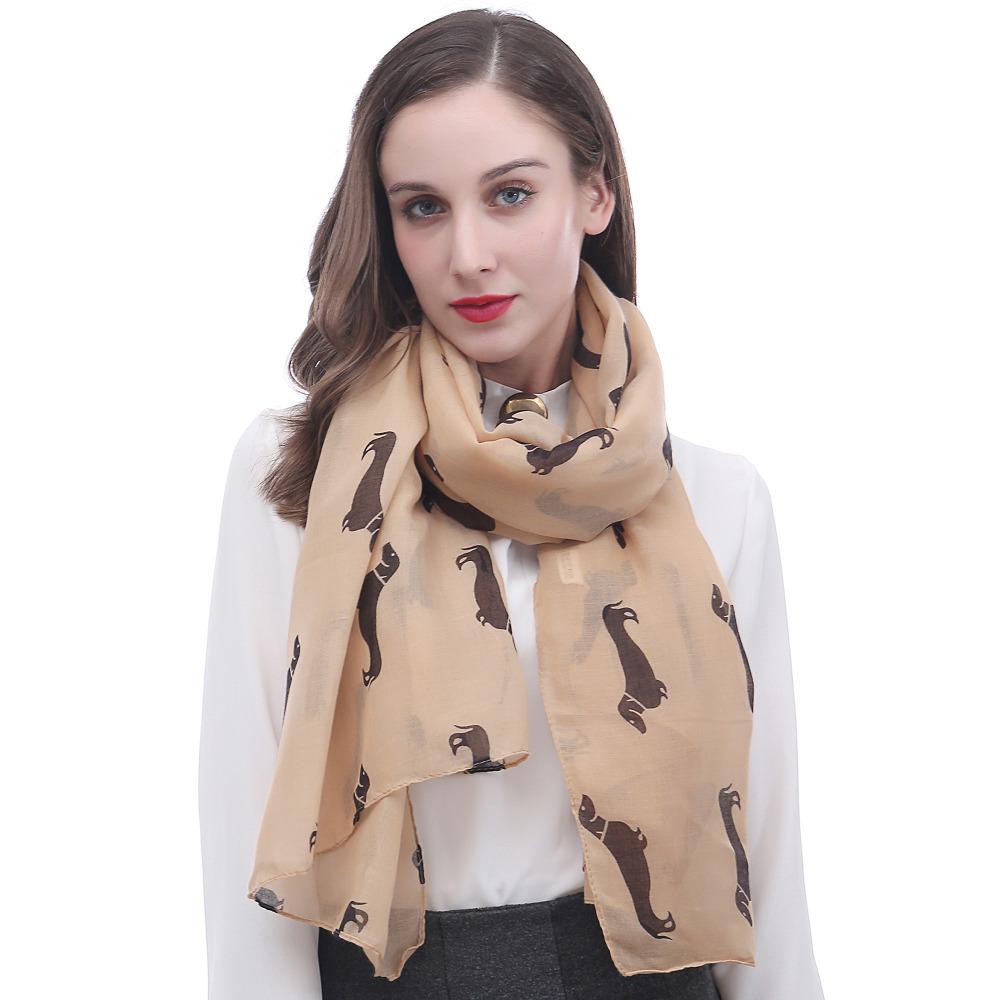 Image of a girl wearing a beautful Dachshund scarf in the color camel with infinite Dachshunds design