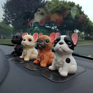 Image of four french bulldog figurines sitting on car dashboard