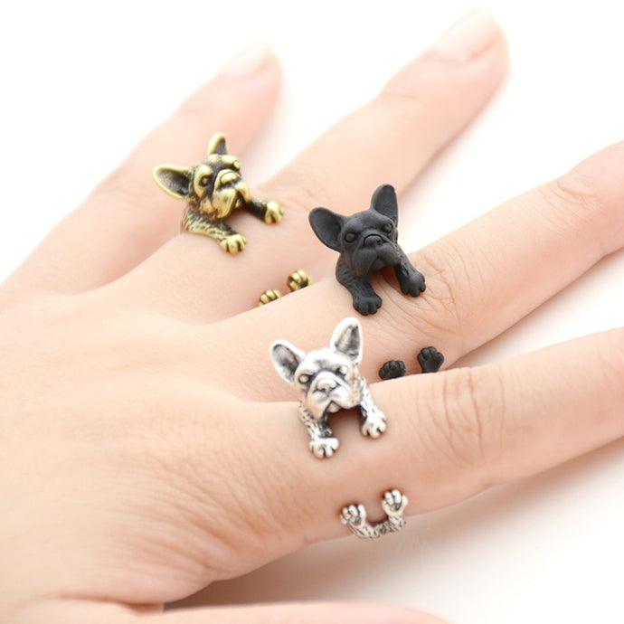 Image of three finger wrap french bulldog rings on the finger of a person in three colors including Antique Silver, Bronze, and Black Gunmetal