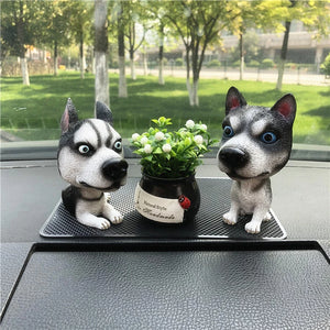 Image of a standing and sitting siberian husky bobbleheads on car dashboard